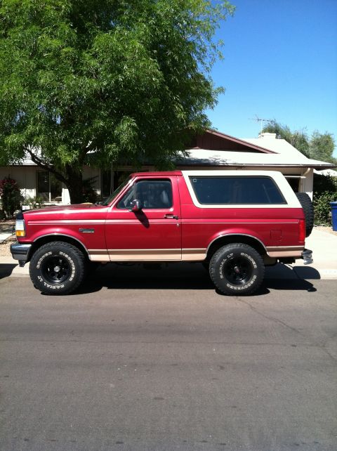 1994 Ford Bronco - This red Ford Bronco is shown from the side, a two-tone paint scheme and a spare tire mounted on the rear.