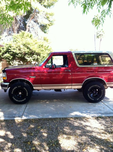 1994 Ford Bronco - This red Ford Bronco, seen from the side, appears to be from the early to mid-1990s.