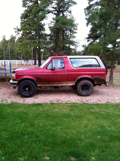 1994 Ford Bronco - Side view of a red 1994 Ford Bronco parked on a gravel driveway.