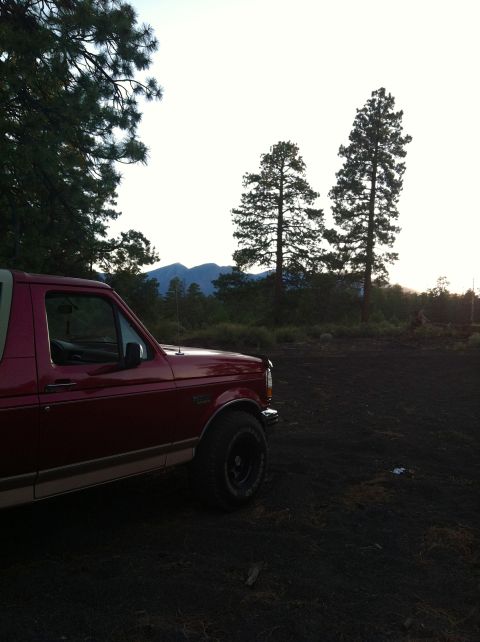 1994 Ford Bronco - A red SUV is parked in a natural landscape with trees and mountains visible.