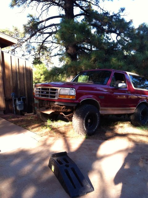 1994 Ford Bronco - This Ford Bronco is parked outside next to a wooden fence and a large tree.