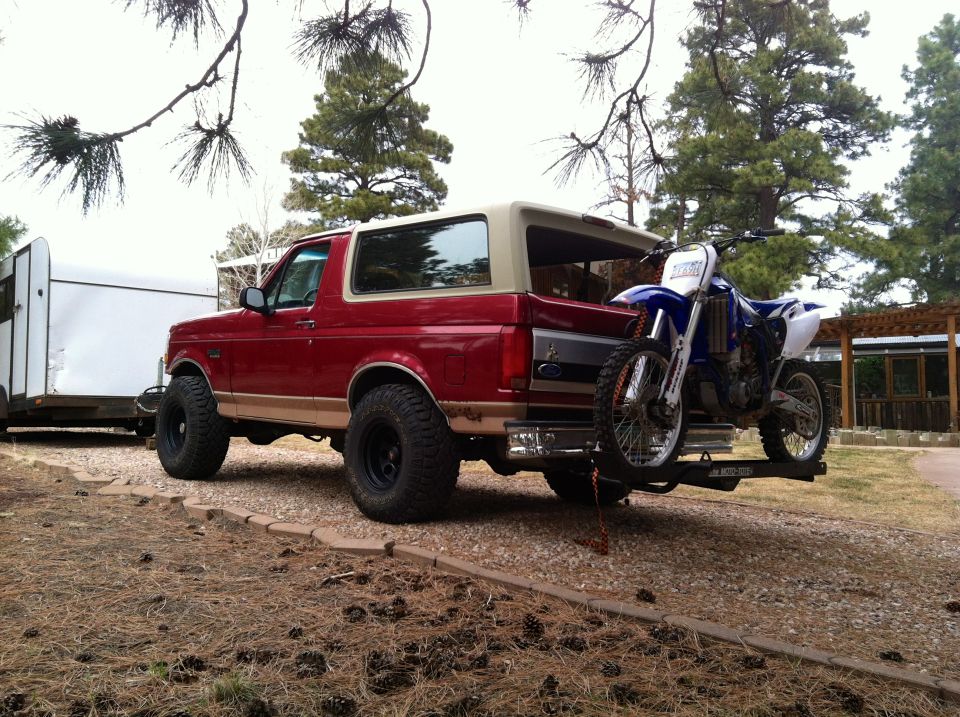 Red SUV towing a trailer with a dirt bike mounted on the back hitch