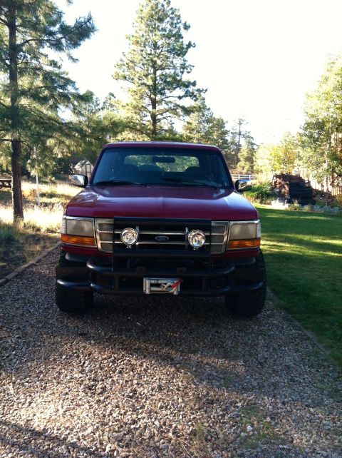 1994 Ford Bronco - Front view of a red Ford Bronco with a black bull bar and auxiliary lights.