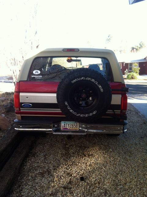 1994 Ford Bronco - Rear view of a red and tan Ford Bronco, showing its spare tire and license plate.