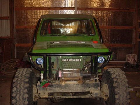 1992 Ford Bronco - This green off-road vehicle has a roll cage and a winch mounted on the front.