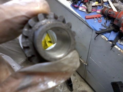 1998 Ford Crown Victoria - A metal gear is held up for inspection, with tools and other parts visible in the background.