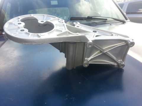 1994 Ford Bronco - Aluminum bracket part shown on a dark blue surface with a Supermotors logo in the corner.