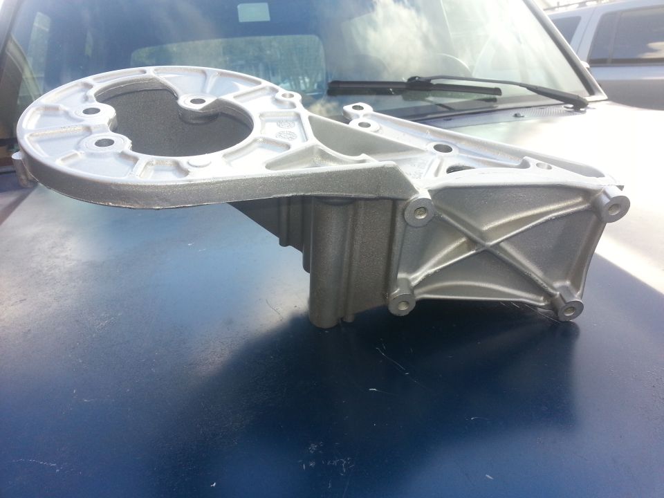 Aluminum bracket part on dark blue surface, Supermotors logo visible