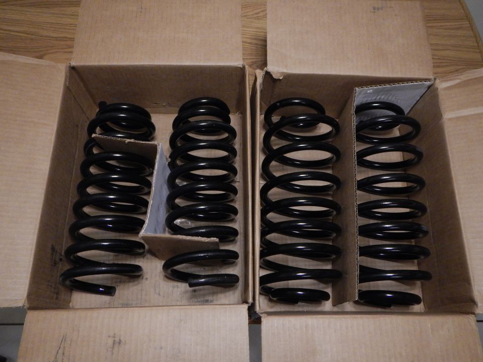 Four black coil springs in two open cardboard boxes