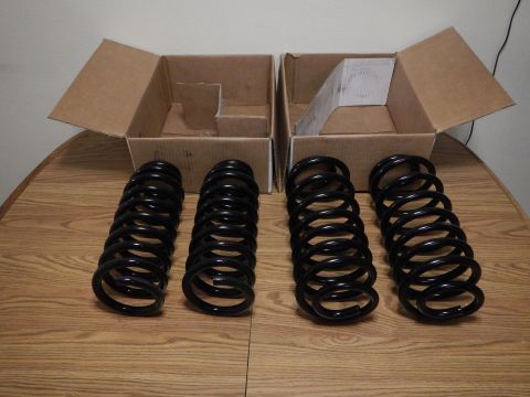 2003 Ford Crown Victoria - Four black coil springs stood upright on a wood-grain table in front of two open cardboard boxes.