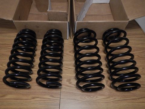 2003 Ford Crown Victoria - Four black coil springs stood upright on a wood-grain table in front of two open cardboard boxes.