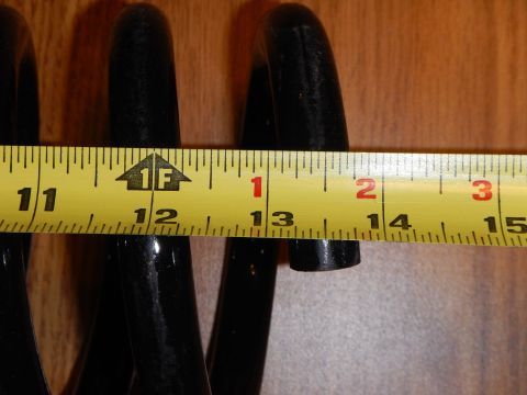 2003 Ford Crown Victoria - black coil spring laid against a tape measure on wood, spanning roughly the 11 to 13 inch marks.