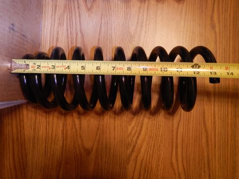 2003 Ford Crown Victoria - long black coil spring laid horizontally on wood beside an extended tape measure for length reference.