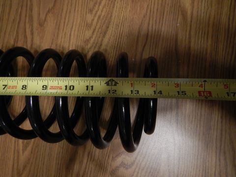 2003 Ford Crown Victoria - black coil spring laid on a wood surface beside a tape measure reading roughly 7 to 17 inches.