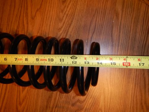 2003 Ford Crown Victoria - black coil spring laid horizontally on a wood-grain table next to an extended tape measure.