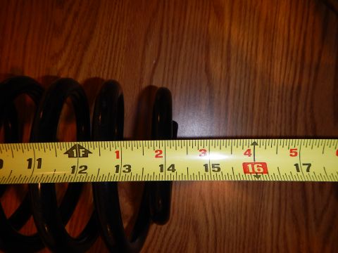 2003 Ford Crown Victoria - black coil spring partly visible behind an extended yellow tape measure on a wood-grain surface.