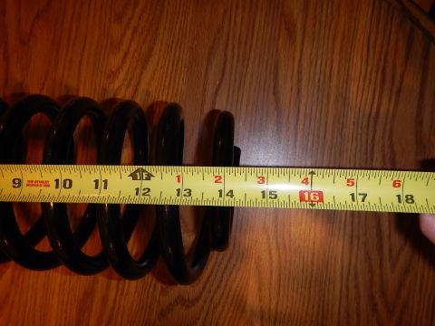 2003 Ford Crown Victoria - black coil spring laid horizontally on a wood-grain surface beside an extended tape measure.