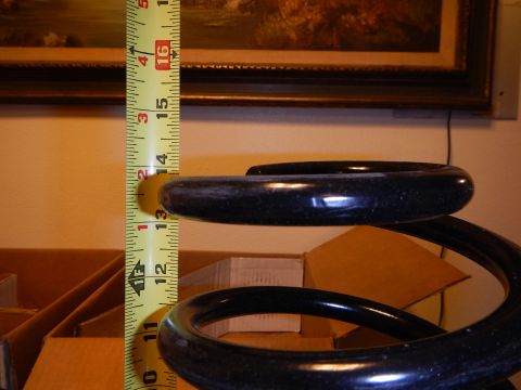 2003 Ford Crown Victoria - glossy dark coil spring stood upright next to a vertical tape measure in front of a framed landscape painting.