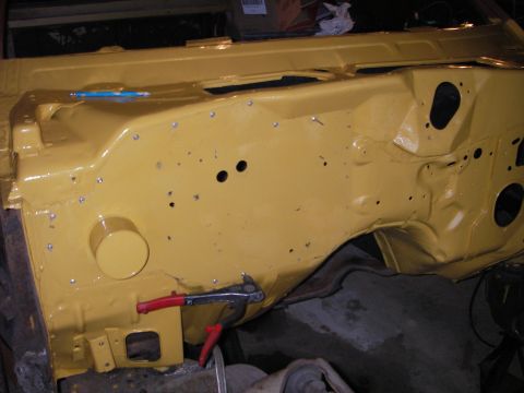 1972 Ford Ranchero - The firewall of a 1972 Ford Ranchero, painted yellow, shows its construction with numerous rivets and openings.