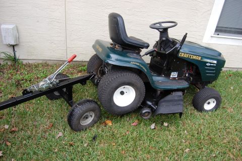 2006 Honda RANCHER - Craftsman riding mower attached to a trailer hitch, parked on grass.