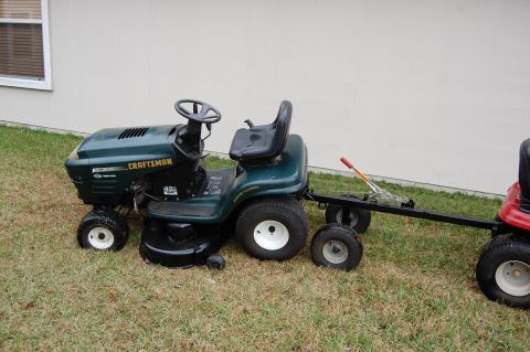 2006 Honda RANCHER - A green Craftsman riding lawn mower is shown towing a red mower attached to a trailer.