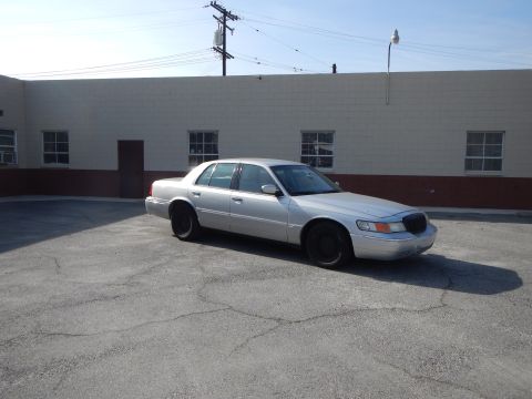 2002 Mercury Grand Marquis - Silver 2002 Mercury Grand Marquis parked in a lot with a building in the background.