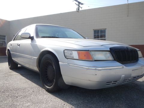 2002 Mercury Grand Marquis - A silver 2002 Mercury Grand Marquis is parked outside a building.
