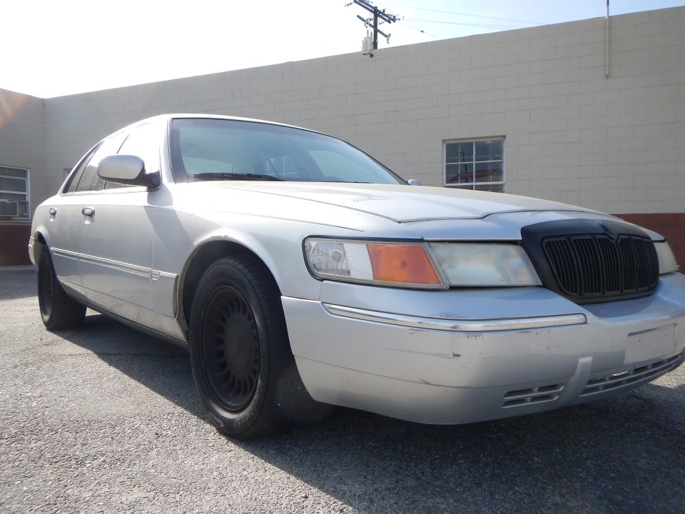 Silver 2002 Mercury Grand Marquis with black grille and black wheels, front 3/4 view