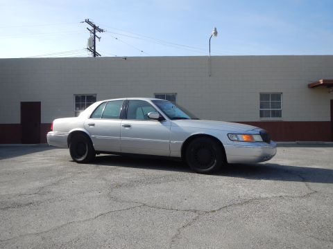 2002 Mercury Grand Marquis - A silver 2002 Mercury Grand Marquis sedan is parked outdoors in front of a building.