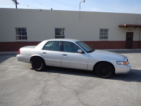 2002 Mercury Grand Marquis - A silver 2002 Mercury Grand Marquis is parked in front of a commercial building.