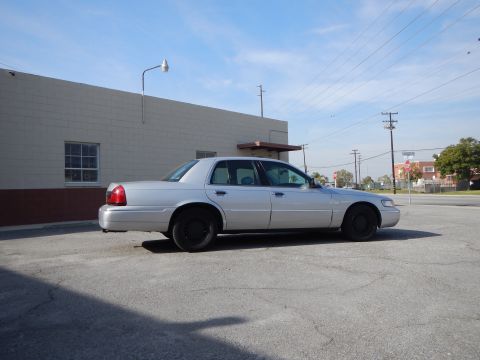 2002 Mercury Grand Marquis - A silver 2002 Mercury Grand Marquis sedan is parked outside a building under a blue sky.