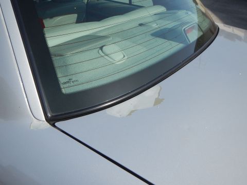 2002 Mercury Grand Marquis - Close-up of a car's rear window and trunk lid, showing a Ford logo etched into the glass.