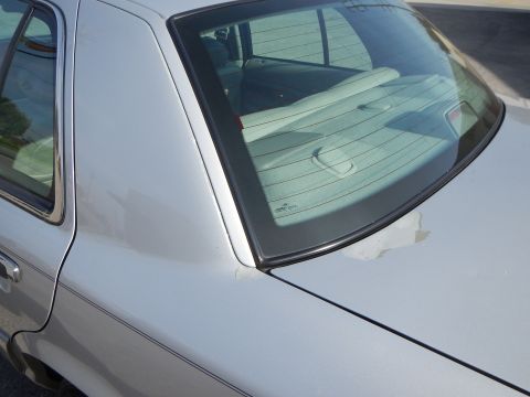 2002 Mercury Grand Marquis - The rear quarter panel and window of a silver sedan are visible, with some paint fading on the trunk.