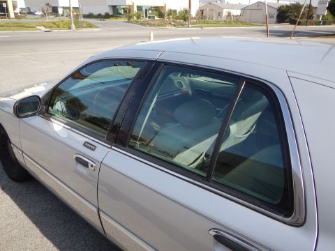 2002 Mercury Grand Marquis - Side profile of a silver 2002 Mercury Grand Marquis, revealing its interior through the tinted windows.