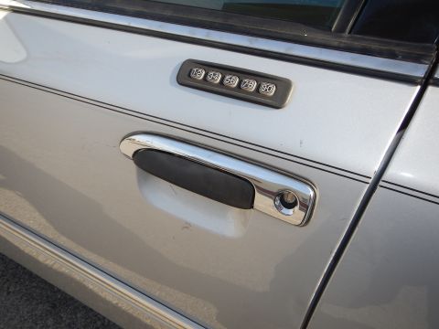 2002 Mercury Grand Marquis - Close-up of a silver 2002 Mercury Grand Marquis door, showing the chrome handle and keypad entry system.
