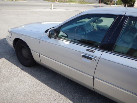 2002 Mercury Grand Marquis - A silver 2002 Mercury Grand Marquis is parked on a street, viewed from the front driver's side quarter panel.