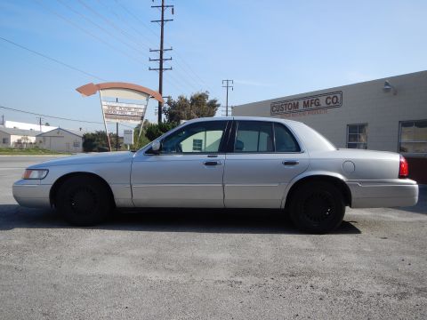 2002 Mercury Grand Marquis - Side view of a silver 2002 Mercury Grand Marquis sedan parked in front of a building.