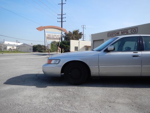 2002 Mercury Grand Marquis - A silver 2002 Mercury Grand Marquis is parked in front of a commercial building.