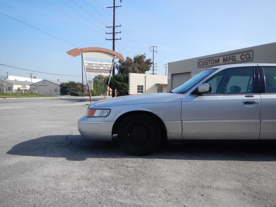 Silver 2002 Mercury Grand Marquis parked outside Custom Mfg. Co