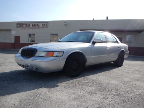2002 Mercury Grand Marquis - A silver 2002 Mercury Grand Marquis sedan is shown from a three-quarter front angle in front of a commercial building.