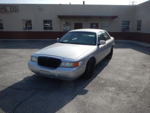 2002 Mercury Grand Marquis - A silver 2002 Mercury Grand Marquis sedan is parked in front of a commercial building.