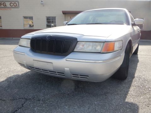 2002 Mercury Grand Marquis - A silver sedan, possibly a Mercury Grand Marquis, is parked in front of a building with a black grille.