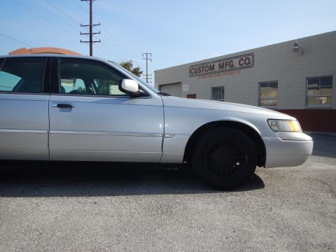 2002 Mercury Grand Marquis - A silver 2002 Mercury Grand Marquis is parked in front of a commercial building.