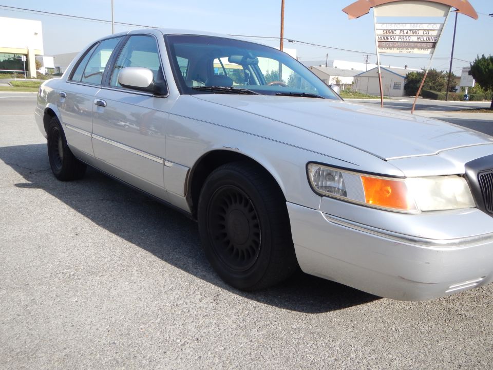 Silver 2002 Mercury Grand Marquis sedan with black wheels parked on asphalt