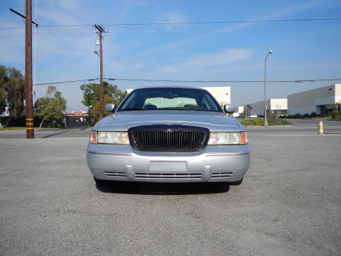 2002 Mercury Grand Marquis - A silver 2002 Mercury Grand Marquis is shown from the front in an outdoor parking lot with buildings and utility poles visible.