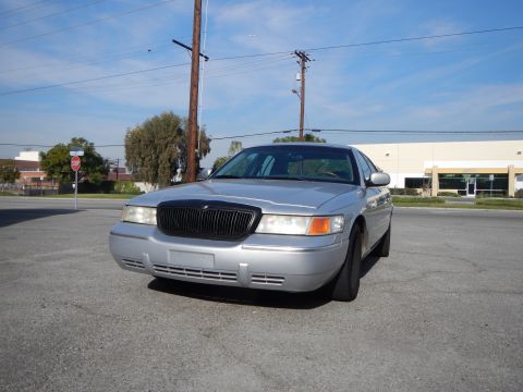 2002 Mercury Grand Marquis - Front view of a silver 2002 Mercury Grand Marquis, a blacked-out grille and a clear blue sky overhead.
