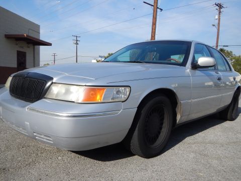 2002 Mercury Grand Marquis - A silver 2002 Mercury Grand Marquis is parked on a paved surface under a clear sky.
