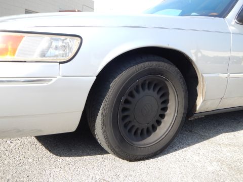 2002 Mercury Grand Marquis - The front passenger side of a silver 2002 Mercury Grand Marquis is visible, focusing on the wheel and fender area.