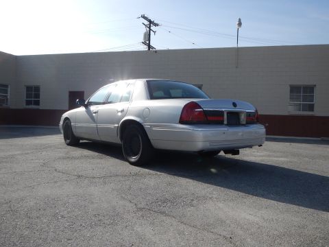 2002 Mercury Grand Marquis - A silver 2002 Mercury Grand Marquis is parked in front of a building on a sunny day.