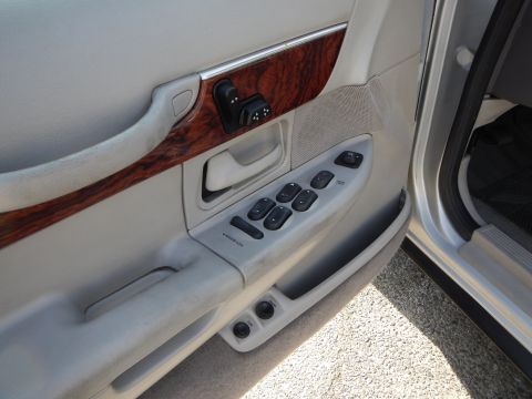 2002 Mercury Grand Marquis - The interior door panel of a 2002 Mercury Grand Marquis features wood grain trim and multiple power controls.